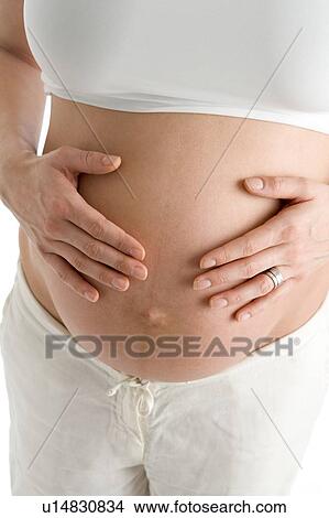 Pregnant woman holding exposed belly View Large Photo Image Picture - Pregnant woman holding exposed belly. Fotosearch