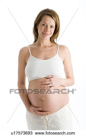 Stock Image - Pregnant woman holding exposed belly smiling. Fotosearch