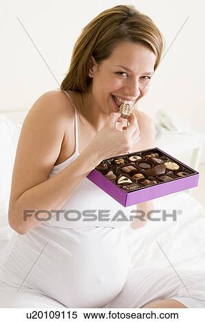 Pregnant woman in bed eating chocolate smiling View Large Photo Image Stock Photography - Pregnant woman in bed eating chocolate smiling. Fotosearch