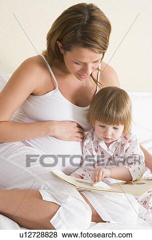 Pregnant woman in bedroom reading book with daughter View Large Photo Image Stock Photo - Pregnant woman in bedroom reading book with daughter. Fotosearch