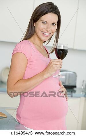 Pregnant woman in kitchen with glass of red wine smiling View Large Photo Image Stock Image - Pregnant woman in kitchen with glass of red wine smiling. Fotosearch