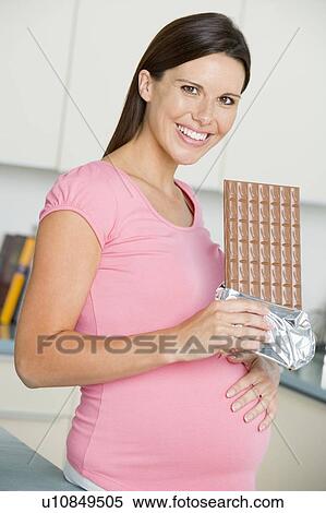 Pregnant woman in kitchen with large chocolate bar smiling View Large Photo Image Stock Photography - Pregnant woman in kitchen with large chocolate bar smiling. Fotosearch