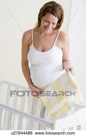 Pregnant woman setting up baby crib smiling View Large Photo Image Stock Photograph - Pregnant woman setting up baby crib smiling. Fotosearch