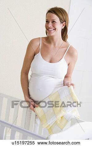 Pregnant woman setting up baby crib smiling View Large Photo Image Stock Photography - Pregnant woman setting up baby crib smiling. Fotosearch