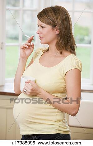 Pregnant woman standing in kitchen with coffee and cigarette View Large Photo Image Stock Photography - Pregnant woman standing in kitchen with coffee and cigarette. Fotosearch