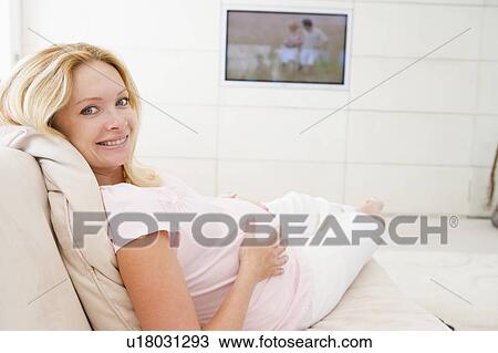 Pregnant woman watching television smiling View Large Photo Image Stock Image - Pregnant woman watching television smiling. Fotosearch