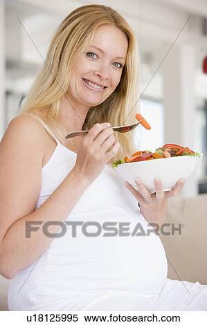 Stock Photography - Pregnant woman with bowl of salad smiling. Fotosearch