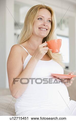 Stock Image - Pregnant woman with cup of tea smiling. Fotosearch