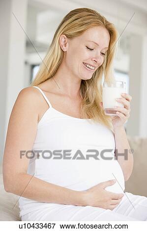 Stock Photo - Pregnant woman with glass of milk smiling. Fotosearch