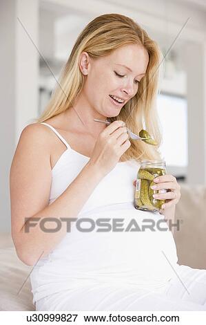 Stock Photo - Pregnant woman with pickles smiling. Fotosearch