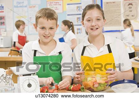 Stock Image - Male and female student preparing sliced fruit. Fotosearch