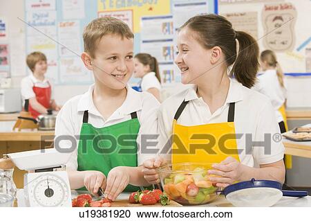 Stock Image - Male and female student preparing sliced fruit. Fotosearch