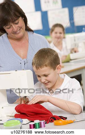 Stock Photo - Male student using sewing machine with teacher. Fotosearch