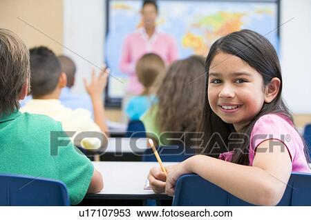Student in class looking at camera with teacher in background (selective focus) View Large Photo Image Stock Image - Student in class looking at camera with teacher in background (selective focus). Fotosearch