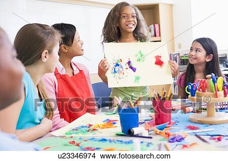 Student showing teacher and classmates her artwork (selective focus) View Large Photo Image Picture - Student showing teacher and classmates her artwork (selective focus). Fotosearch