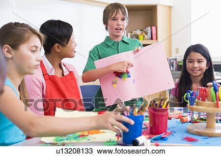 Stock Image - Student showing teacher and classmates his artwork (selective focus). Fotosearch