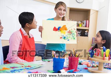 Student showing teacher and classmates her artwork (selective focus) View Large Photo Image Stock Photo - Student showing teacher and classmates her artwork (selective focus). Fotosearch