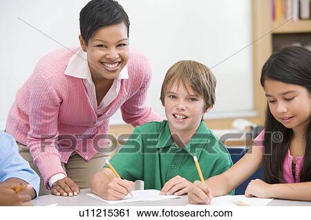 Students in class writing with teacher helping View Large Photo Image Stock Image - Students in class writing with teacher helping. Fotosearch