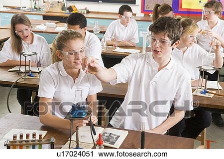 Stock Image - Students performing science experiments in classroom. Fotosearch