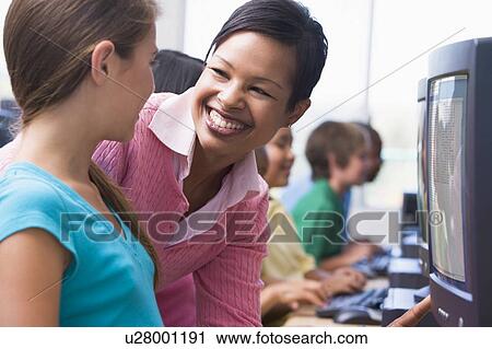 Teacher helping student at computer terminal with students in background (depth of field/high key) View Large Photo Image Stock Image - Teacher helping student at computer terminal with students in background (depth of field/high key). Fotosearch