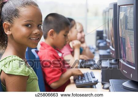Stock Image - Four children at computer terminals (depth of field/high key). Fotosearch