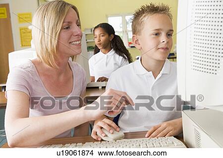 Student and teacher at computer terminal with student in background View Large Photo Image Picture - Student and teacher at computer terminal with student in background. Fotosearch