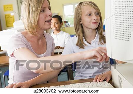 Student and teacher at computer terminal with student in background (selective focus) View Large Photo Image Stock Image - Student and teacher at computer terminal with student in background (selective focus). Fotosearch