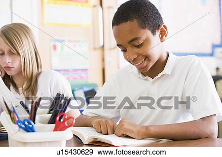 Stock Photo - Student in class reading book. Fotosearch