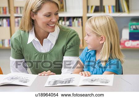 Picture - Student in class reading with teacher. Fotosearch