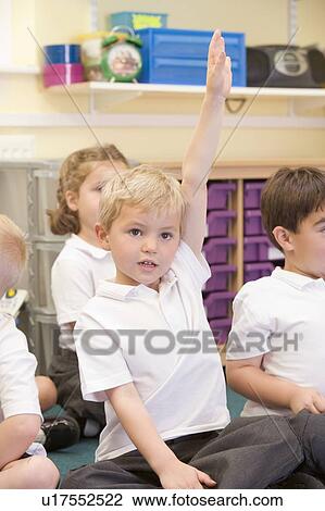 Stock Image - Student in class sitting on floor volunteering (selective focus). Fotosearch
