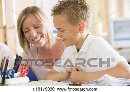 Stock Image - Student in class taking notes with teacher helping. Fotosearch