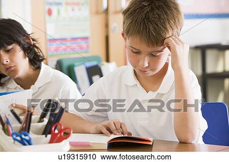 Stock Image - Students in class reading books. Fotosearch