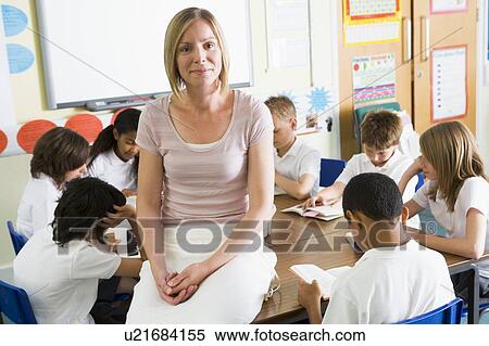 Stock Photography - Students in class reading books with teacher in foreground. Fotosearch