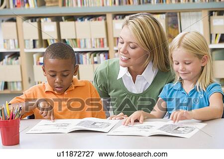 Two students in class reading with teacher View Large Photo Image Stock Photo - Two students in class reading with teacher. Fotosearch