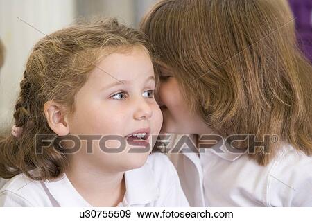 Stock Photo - Two students in class whispering (selective focus). Fotosearch