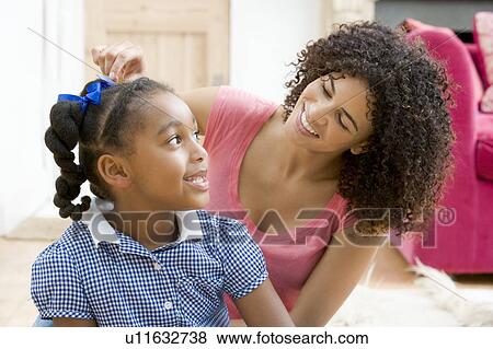 Woman in front hallway fixing young girl's hair and smiling View Large Photo Image Stock Photo - Woman in front hallway fixing young girl's hair and smiling. Fotosearch