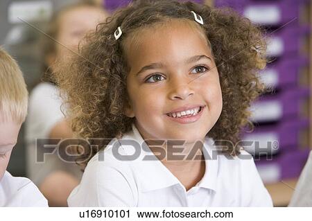 Stock Image - Student in class sitting on floor with students in background (selective focus). Fotosearch