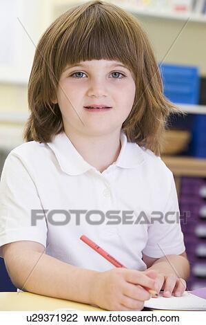 Stock Image - Student in class writing in notebook (selective focus). Fotosearch