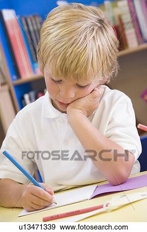 Stock Photo - Student in class writing in notebook (selective focus). Fotosearch