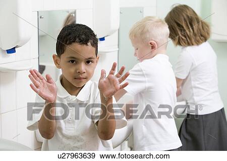 Students in bathroom at sinks washing hands with one holding up soapy hands (selective focus) View Large Photo Image Stock Photo - Students in bathroom at sinks washing hands with one holding up soapy hands (selective focus). Fotosearch