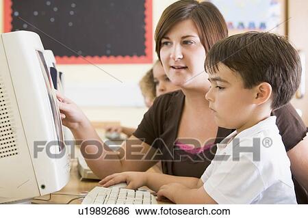 Stock Photograph - Students in class at computer terminals with teacher (selective focus). Fotosearch