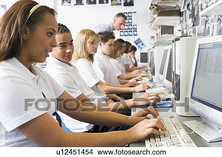 Picture - Students working on computer workstations with teacher. Fotosearch