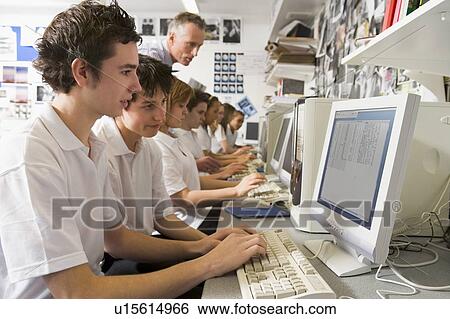 Stock Photograph - Students working on computer workstations with teacher. Fotosearch