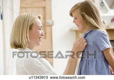 Woman in front hallway fixing young girl's dress and smiling View Large Photo Image Stock Image - Woman in front hallway fixing young girl's dress and smiling. Fotosearch
