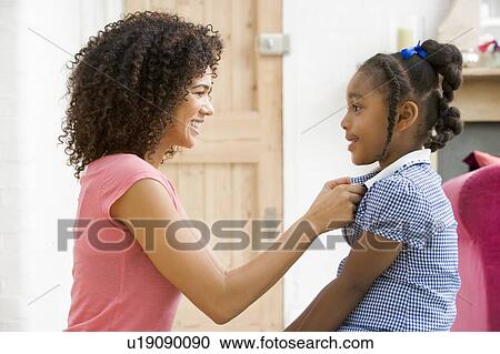 Woman in front hallway fixing young girl's dress and smiling View Large Photo Image Stock Image - Woman in front hallway fixing young girl's dress and smiling. Fotosearch