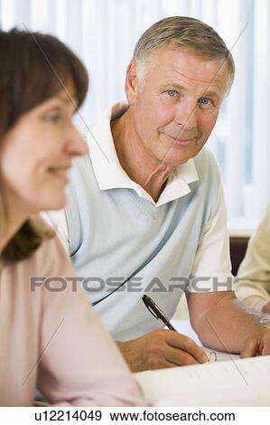 Stock Photo - Adult students studying at table (selective focus). Fotosearch