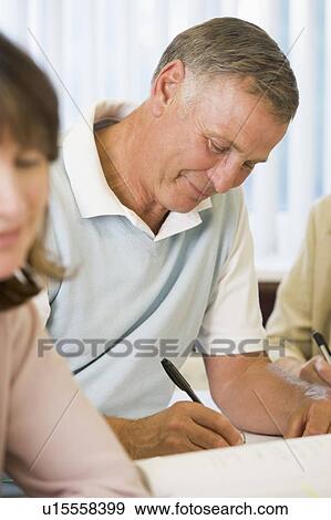 Stock Photo - Adult students studying at table (selective focus). Fotosearch