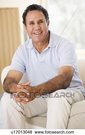Man in living room smiling View Large Photo Image Stock Photo - Man in living room smiling. Fotosearch