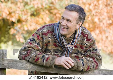Man outdoors at park leaning on fence smiling (selective focus) View Large Photo Image Stock Image - Man outdoors at park leaning on fence smiling (selective focus). Fotosearch