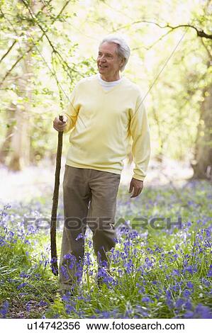 Man walking outdoors with walking stick smiling View Large Photo Image Stock Photograph - Man walking outdoors with walking stick smiling. Fotosearch